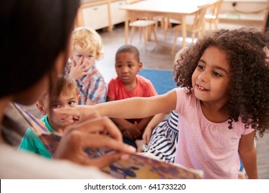 Pupils At Montessori School Looking At Book With Teacher - Shutterstock ID 641733220