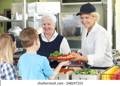 Pupils In School Cafeteria Being Served Lunch By Dinner Ladies