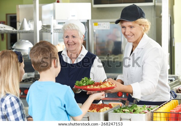 Pupils In School Cafeteria Being Served Lunch By\
Dinner Ladies