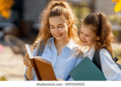 Pupils of the school. Girls with backpacks outdoors. Teens are embracing. Beginning of lessons. First day of fall.  - Powered by Shutterstock