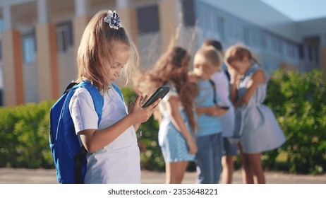 pupils stand in the schoolyard and look at phones. business concept of modern lifestyle training and development. a lifestyle group of students playing on the phone in the backyard of the school - Powered by Shutterstock