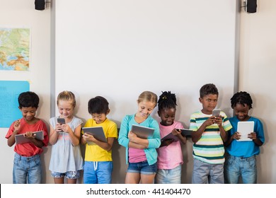 Pupils Standing With Technology In Classroom