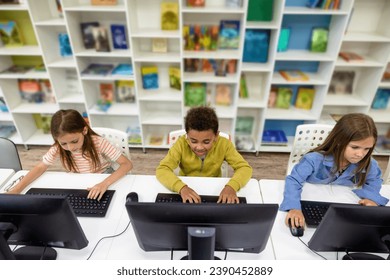 Pupils studying on computers in school library.