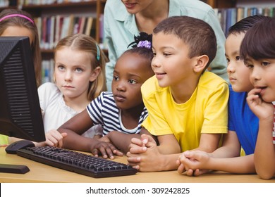 Pupils And Teacher In The Library Using Computer At The Elementary School