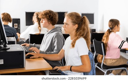 Pupils using computers at lesson, teacher teaching them in classroom