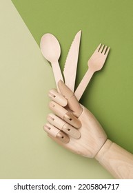 Puppet Hand Holding Wooden Fork, Spoon And Knife On Green Background. Eco-friendly, Zero Waste Concept