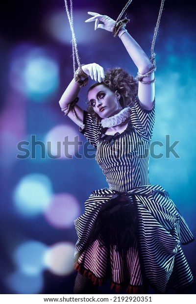 Puppet theater and circus. The actress plays a\
doll on strings at a performance in a puppet theater. Dark\
background with shining\
lights.