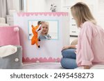 Puppet theatre. Smiling girl performing show with toy to her mother at home