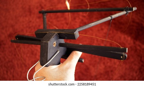 puppeteer hand with a puppeteer's crossbar tool of wood or wooden crosshead painted in black, with strings to hang a puppet isolated over a red carpet background - traditional instrument for masters - Shutterstock ID 2258189451