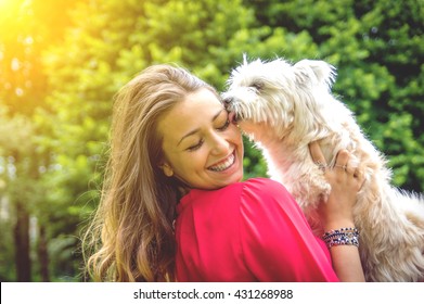 Puppy white dog licking it's owner. Attractive caucasian girl having fun with her dog