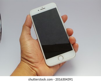 Purbalingga July 2021 - person holding a white iPhone 8 isolated on a white background. INDONESIA