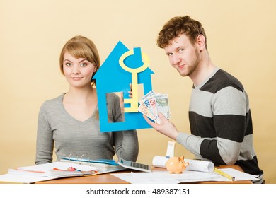 Purchase And Construction Investment. Just Married Lovely Couple With Model Of Their New Home House. Woman And Man With Key To Flat Apartment And Cash Money.