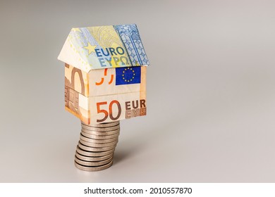 Purchase and sale of housing. Mortgage for the purchase of a house. Rental Property. A house made of euros stands on a stack of coins. Origami. Close-up. Copy space. Housing in Europe