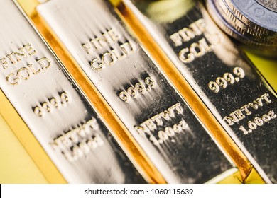 Pure 999.9 shiny fine gold bullions ingot bars with money coins, closed up macro shot as financial asset, investment and wealth concept.
