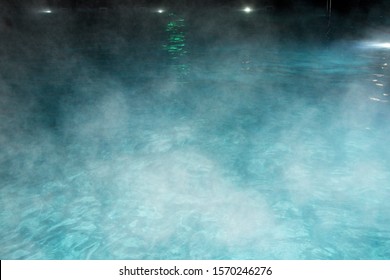 Pure clear water in the thermal pool. Hot water flows, and fog rises above the pool, the pool itself is illuminated by lanterns. Blue water, beautiful background. - Shutterstock ID 1570246276