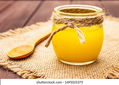 Pure Or Desi Ghee (ghi), Clarified Melted Butter. Healthy Fats Bulletproof Diet Concept Or Paleo Style Plan. Glass Jar, Wooden Spoon On Vintage Sackcloth. Wooden Boards Background, Close Up