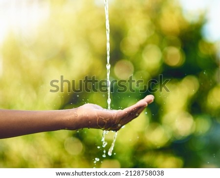 Pure and precious to nature. Shot of hands held out to catch a stream of water outside.