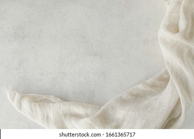Pure Washed Linen Cloth On Light Grunge Stone Background. Natural Washed Linen Fabric On Stone Tile Surface With Copy Space.