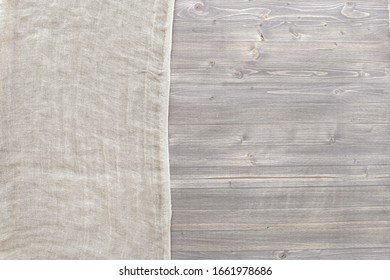 Pure washed linen cloth on grey wooden panel background with copy space. Natural washed linen fabric on wood texture surface with natural striped pattern.
