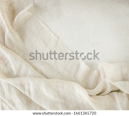 Pure washed linen cloth on light grunge stone background. Natural washed linen fabric on stone tile surface with copy space.