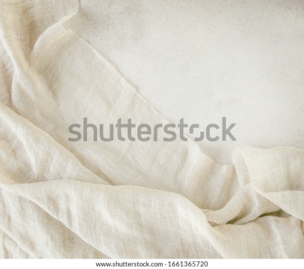 Pure\
washed linen cloth on light grunge stone background. Natural washed\
linen fabric on stone tile surface with copy\
space.