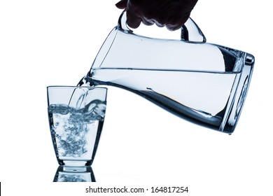 Pure Water Is Emptied Into A Glass Of Water From A Pitcher. Fresh Drinking Water
