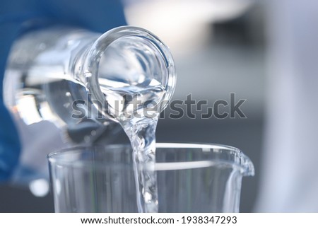 Pure water is poured from glass bottle into glass
