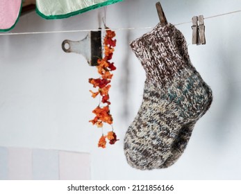 Pure Woolen Socks Hang On A Rope Against The Backdrop Of A Rustic Stove In A Rustic House In Winter.