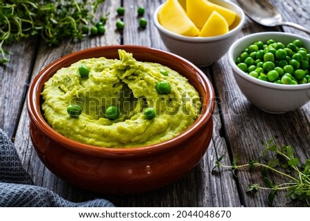 Puree - mashed potatoes with green pea in bowl on wooden table 