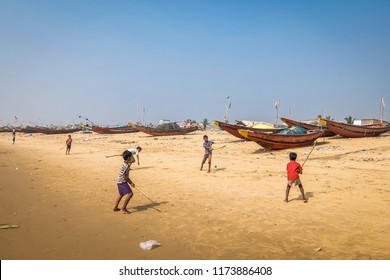 Puri, India - Circa January, 2018. Kids Playing Cricket On The Sandy Beach With Fishing Boats On The Background In Puri.