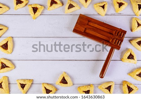 Purim background with noise maker and hamantaschen triangle cookies.