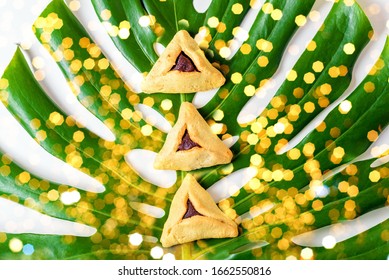 Purim Festive Background With Bokeh Lights. Group Of Variety Triangular Cookies Hamantaschen Traditional Meal For Jewish Holiday Purim On Monstera Leaf.