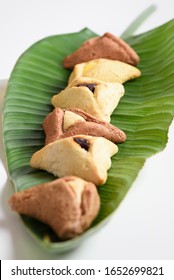 Purim Holiday Concept. Group Of Variety Triangular Cookies Hamantash Traditional Meal For Jewish Holiday Purim On Palm Leaf.