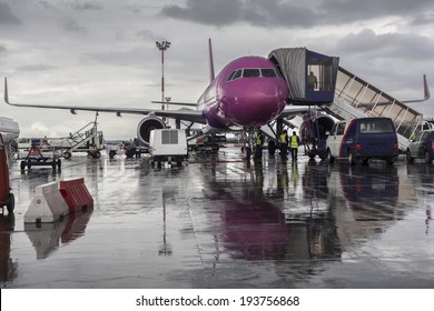 Purple Airplane On The Ground With Maintenance Cars Around