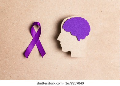 Purple awareness ribbon and brain symbol on a brown background. Epilepsy disease or Alzheimer disease awareness world day.