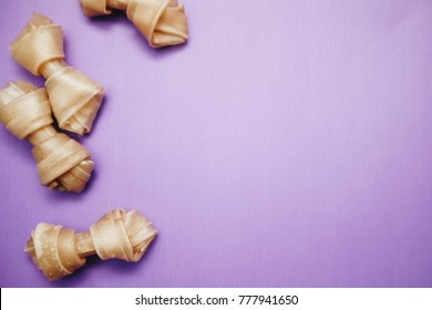 Purple background with twisted dog treats, top view. Pet care and veterinary concept. Spase for your text or image.