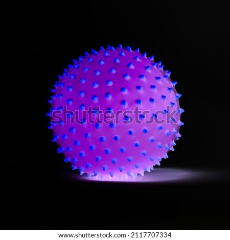 Purple ball with blue spikes isolated and glowing on black background