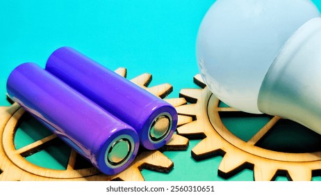 purple battery and white bulb on wooden gear teeth on green background - Powered by Shutterstock