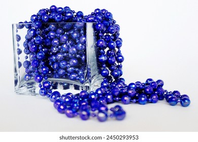 purple beads in a glass vase on a white background