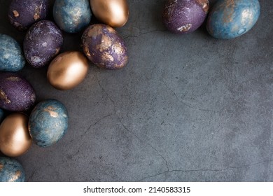 Purple, blue and golden eggs on a dark concrete background. The purple hue trend of 2022 is very peri. Easter card with a copy of the place for the text. Natural dye karkade tea. Top view.