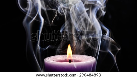 Purple burning candle with flame and smoke on black background.