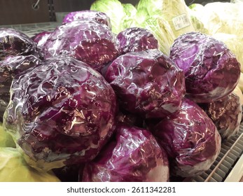 Purple cabbage wrapped in transparent plastic on fresh market display. Brassica oleracea var. capitata f. rubra. Fresh cabbage close up.