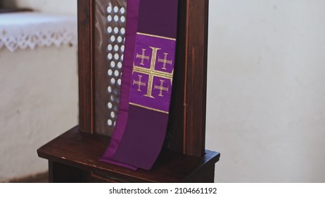 Purple Catholic Priest Stole with Embroidered Jerusalem Cross Hanging Over Grate of Simple Church Confessional