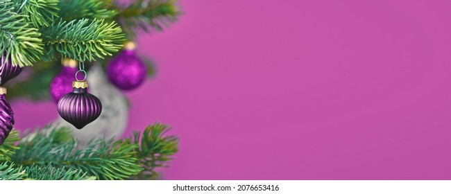 Purple Christmas banner with tree bauble on decorated tree with copy space