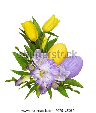 Purple freesia flowers and yellow tulips in a Easter corner floral arrangement with painted eggs isolated on white background