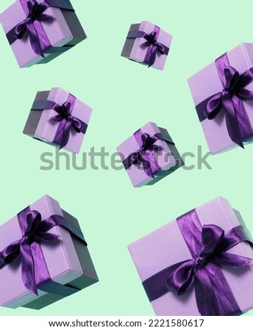 Purple gift box with ribbon flying on pastel green background. Creative realistic minimal gift for Christmas or Holiday giving concept. Visual aesthetic present.