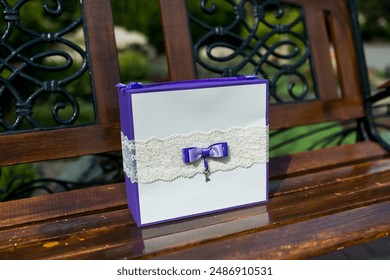 A purple gift box with a white lace ribbon and a purple bow sits on a wooden bench. - Powered by Shutterstock