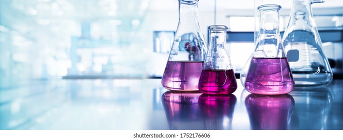 purple glass flask in blue research chemistry science banner laboratory background  - Shutterstock ID 1752176606