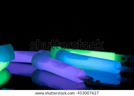 Purple, green and blue glowsticks on a reflective surface