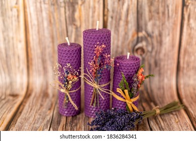 Purple honey candles handmade from natural wax on a background of wooden boards. Elements from natural materials. Christmas or New Year's composition. Photo for postcards.